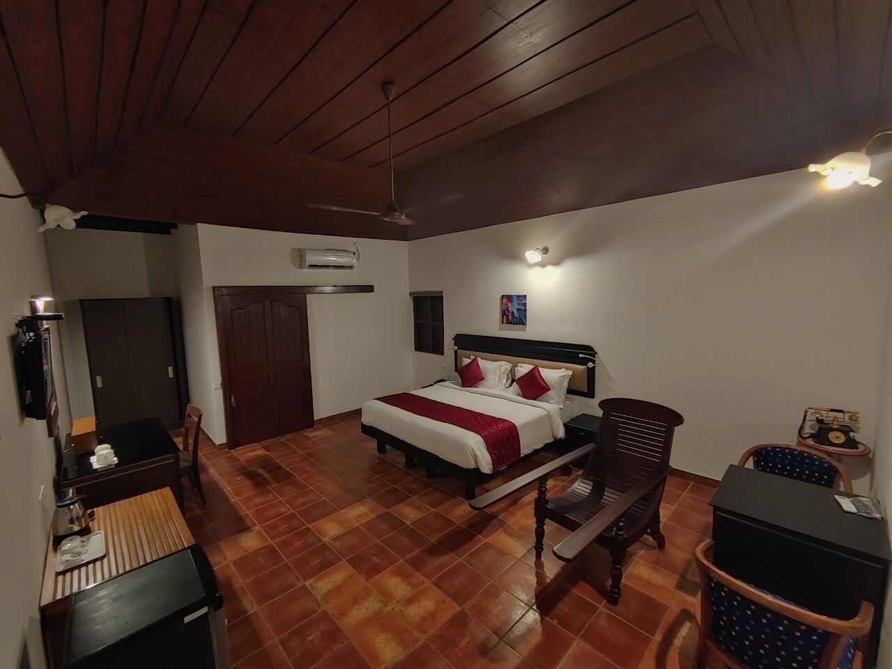 A bedroom with a bed, a desk, a chair, a wardrobe, and a ceiling fan.