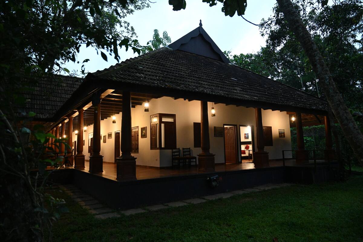 A traditional building with a tiled roof, wooden columns, and a porch with seating.