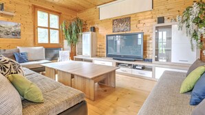 Ein gemütliches Holzhaus-Interieur mit einer Couch, einem Couchtisch, einem Fernseher und einem Schrank.