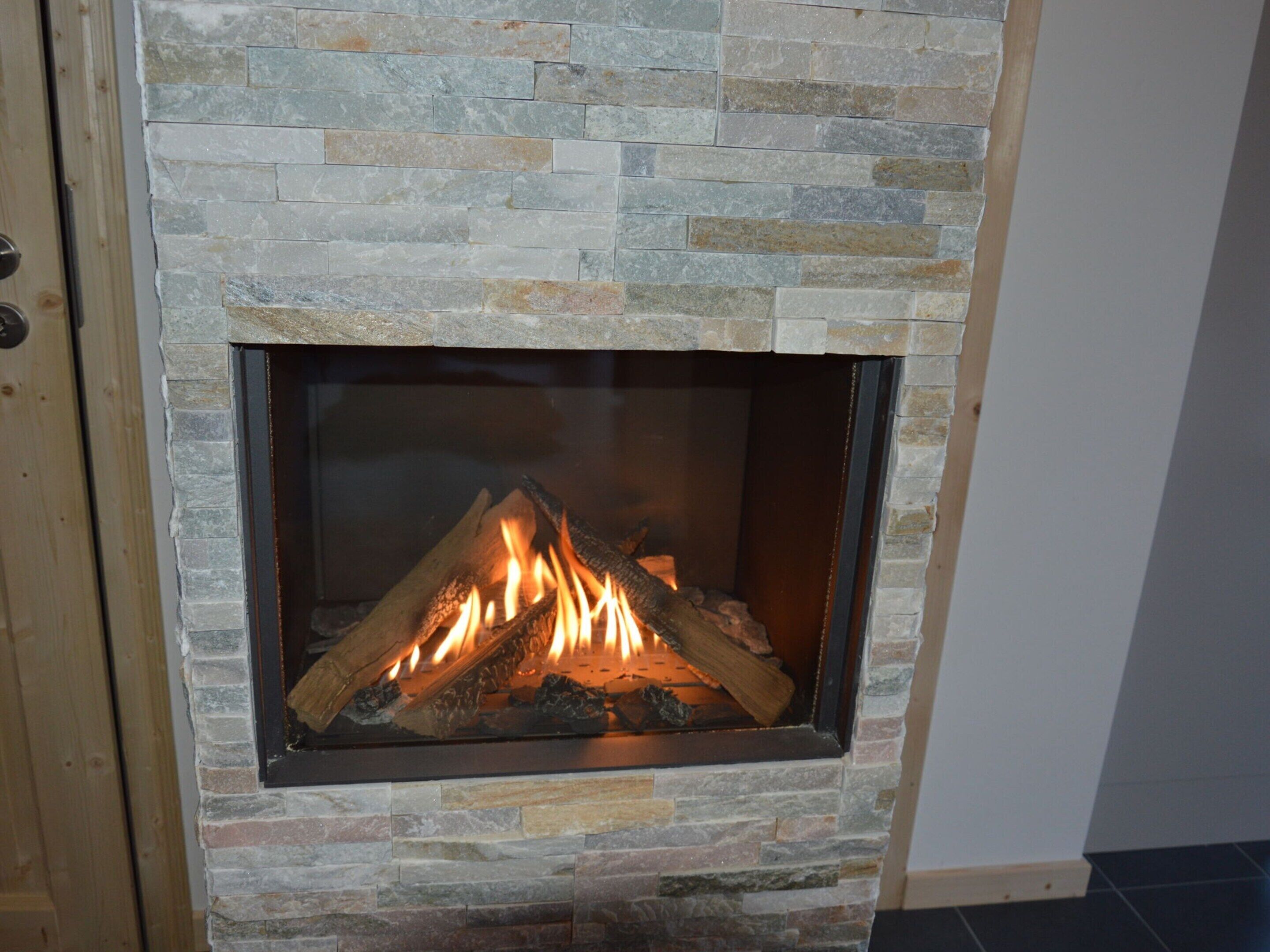 A stone fireplace with a fire burning inside.