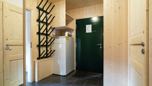 A small, wooden-paneled room with a refrigerator, a green door, and a black metal rack. - Pleasant Chalet With Indoor hot tub (Sankt Georgen am Kreischberg)