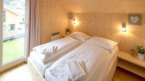 A double bed with white linens in a wooden cabin room with a view of a wooden house outside. - Pleasant Chalet With Indoor hot tub (Sankt Georgen am Kreischberg)