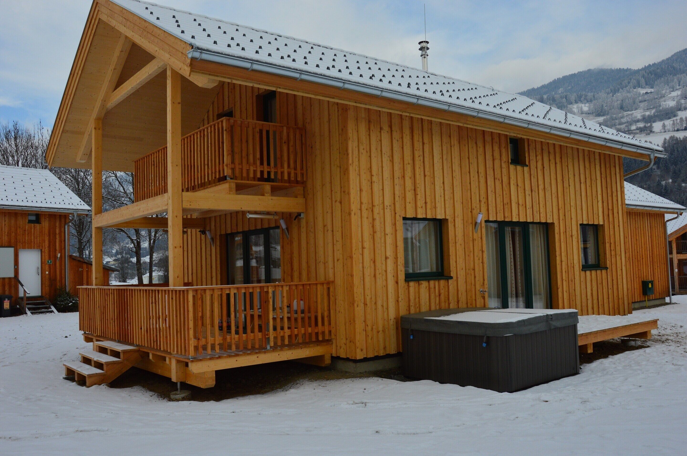 Une cabane en bois dotée d’un balcon, d’un bain à remous et surplombant un paysage enneigé.