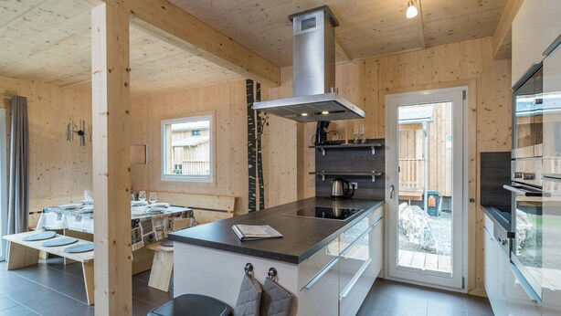 A modern kitchen with wooden walls, a central island, and built-in appliances. - Luxurious Chalet in Sankt Lorenzen ob Murau With Jacuzzi (Sankt Georgen am Kreischberg)