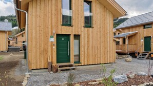 A wooden cabin with a green door, a small porch, and a gravel driveway. - Luxurious Chalet in Sankt Lorenzen ob Murau With Jacuzzi (Sankt Georgen am Kreischberg)