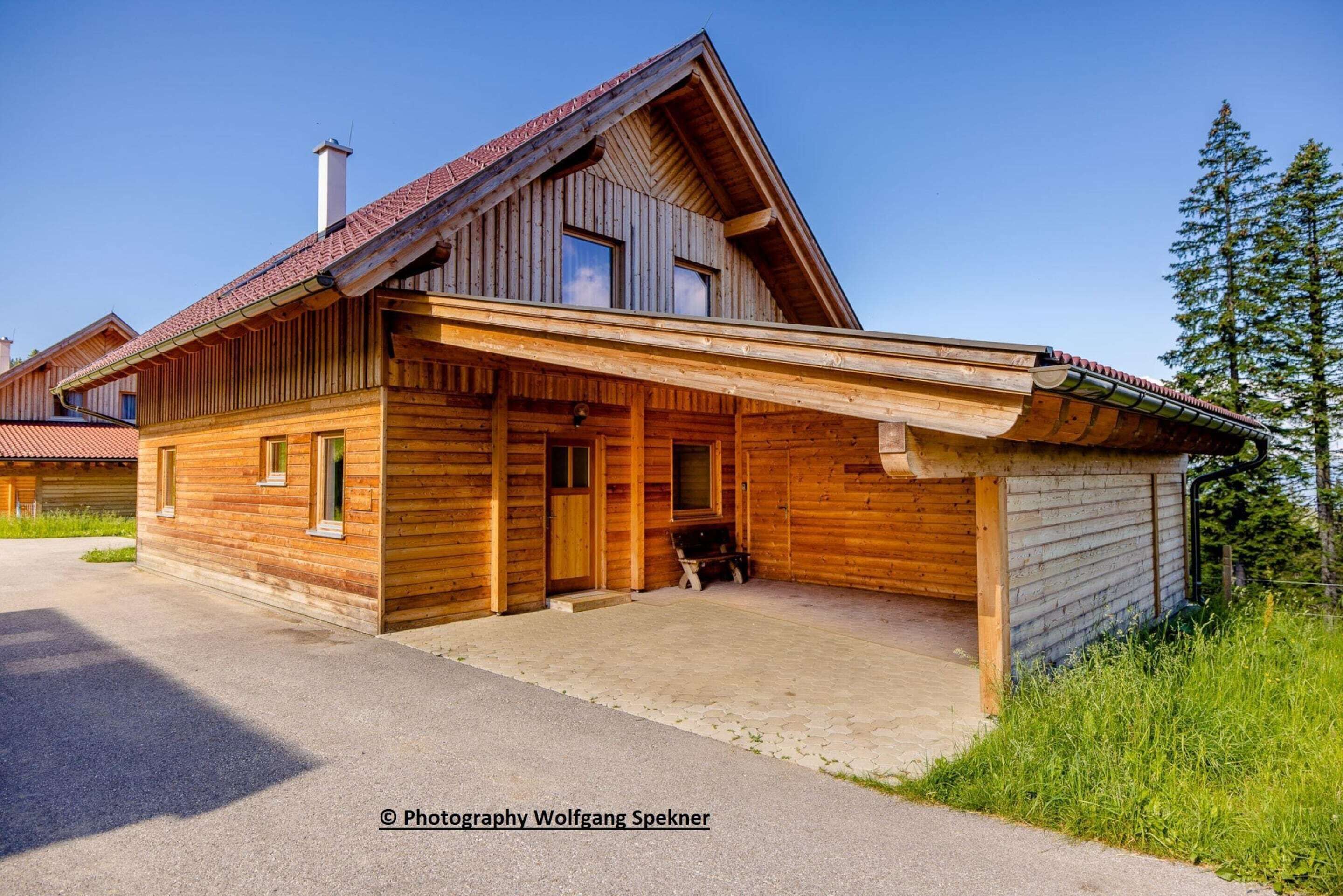 A wooden cabin with a sloped roof, a porch, and a garage.