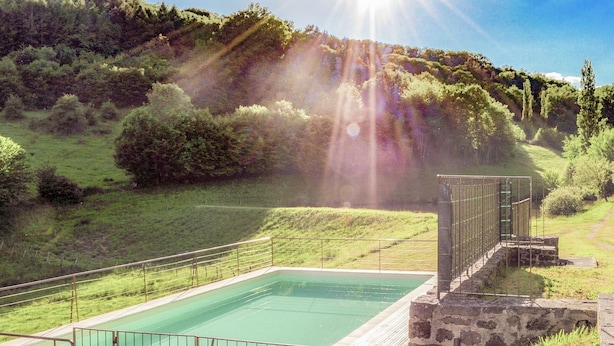A rectangular pool with a stone deck and metal railing, surrounded by a grassy area and trees. - Villa With Pool & Views in Serilhac (Serilhac)
