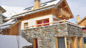 A multi-story wooden building with stone walls, balconies, and windows. - Cosy Valloire Family Chalet (Valloire)