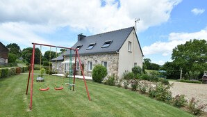 A stone house with a sloped roof, a swing set, and a well-maintained lawn. - Home for 7 Guests in Plouvara (Plouvara)