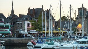 A marina with boats docked, buildings with signage, and a church spire in the background. - Home for 7 Guests in Plouvara (Plouvara)