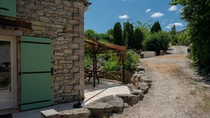 En bygning i sten med en grøn dør, en grussti og en træpergola.