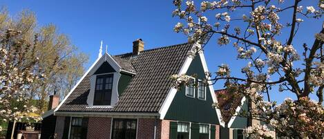 Et traditionelt hus med et stejlt tag, murstensvægge og en grøn facade.