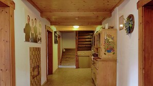 Ein Korridor mit Holzwänden und -decke, einer Treppe und einem Holzschrank mit floralem Dekor.