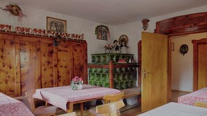 Ein traditionell eingerichteter Raum mit Holzmöbeln, einem grünen Schrank und einem Esstisch mit rosa Tischdecke.