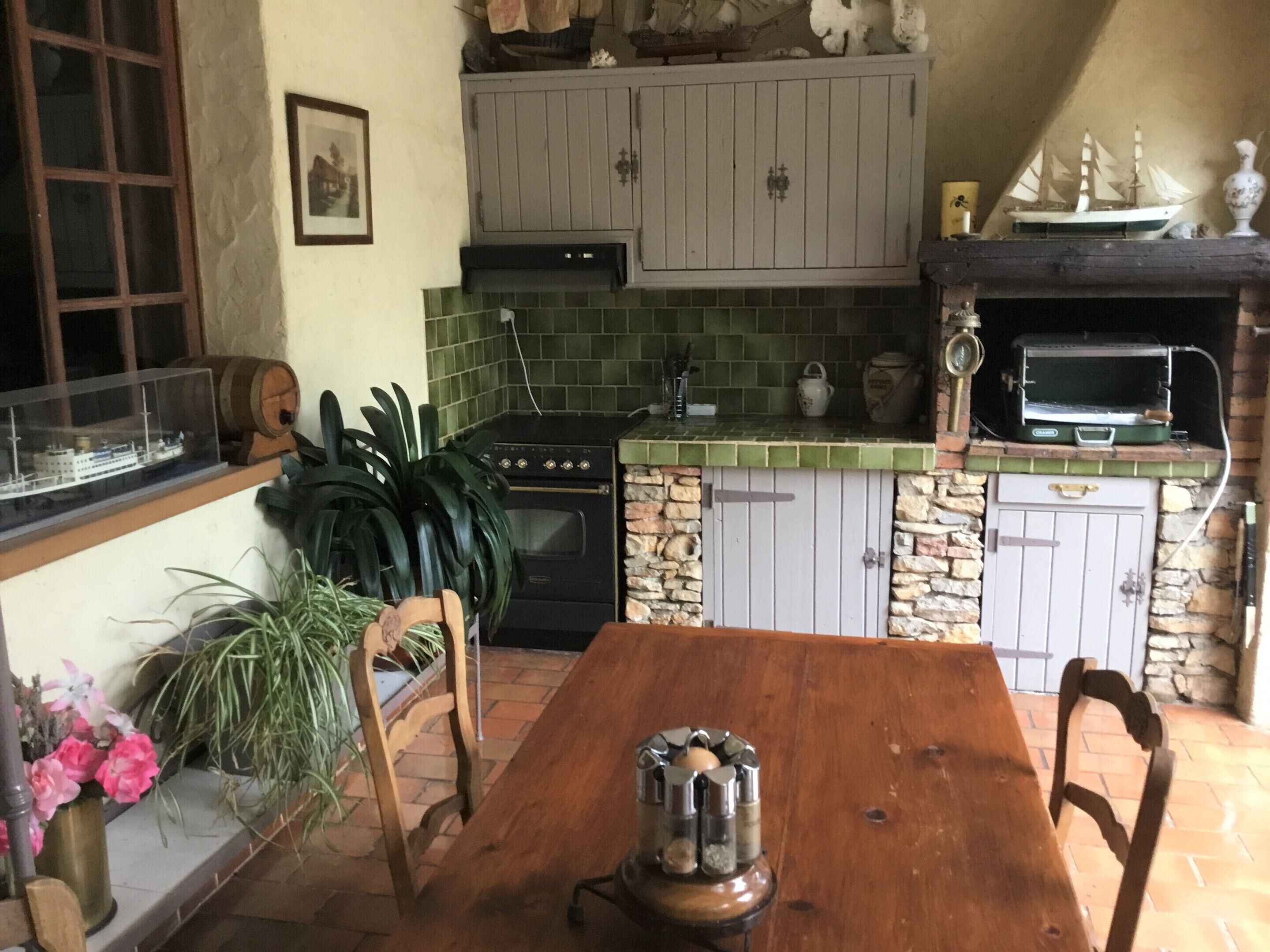 A kitchen with a wooden table, a stove, a sink, and a green tiled backsplash.