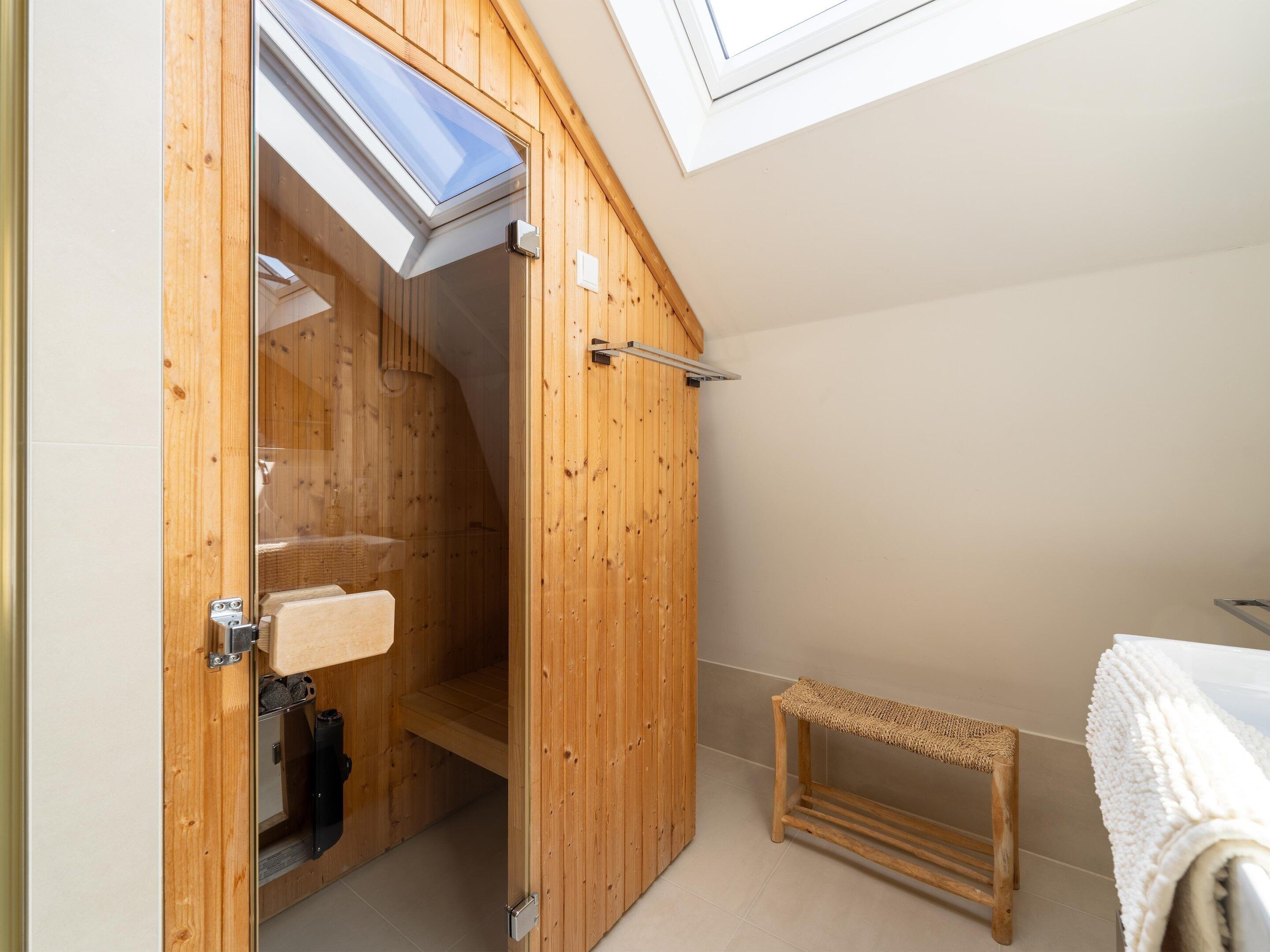 A wooden room with a skylight, a bench, and a towel rack.