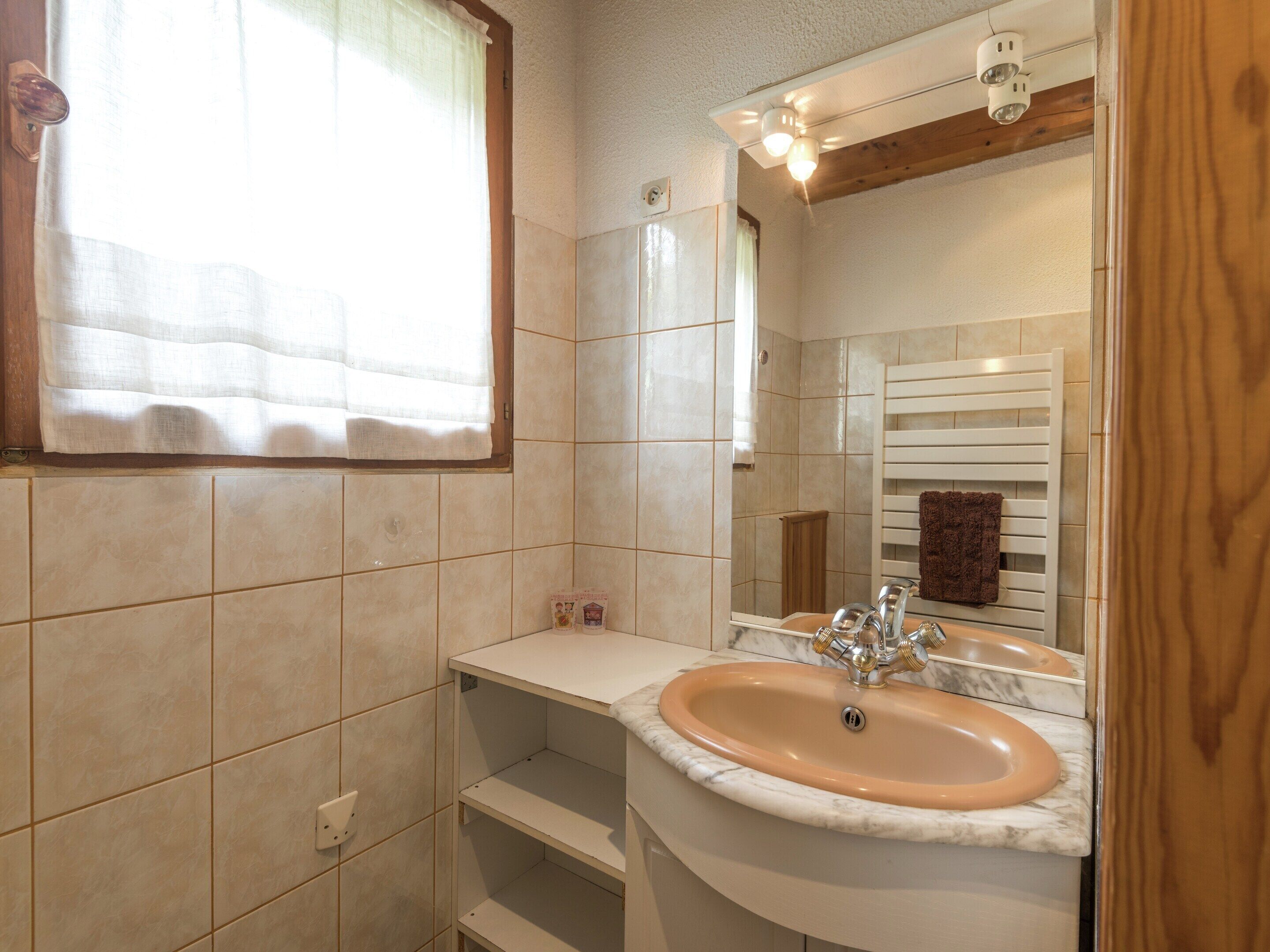 Casa de banho com lavatório, espelho e porta-toalhas.