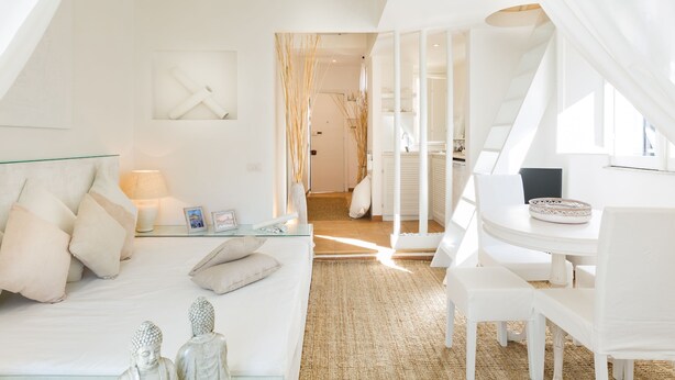 A modern, white-themed bedroom with a bed, bedside table, and a view into the bathroom.