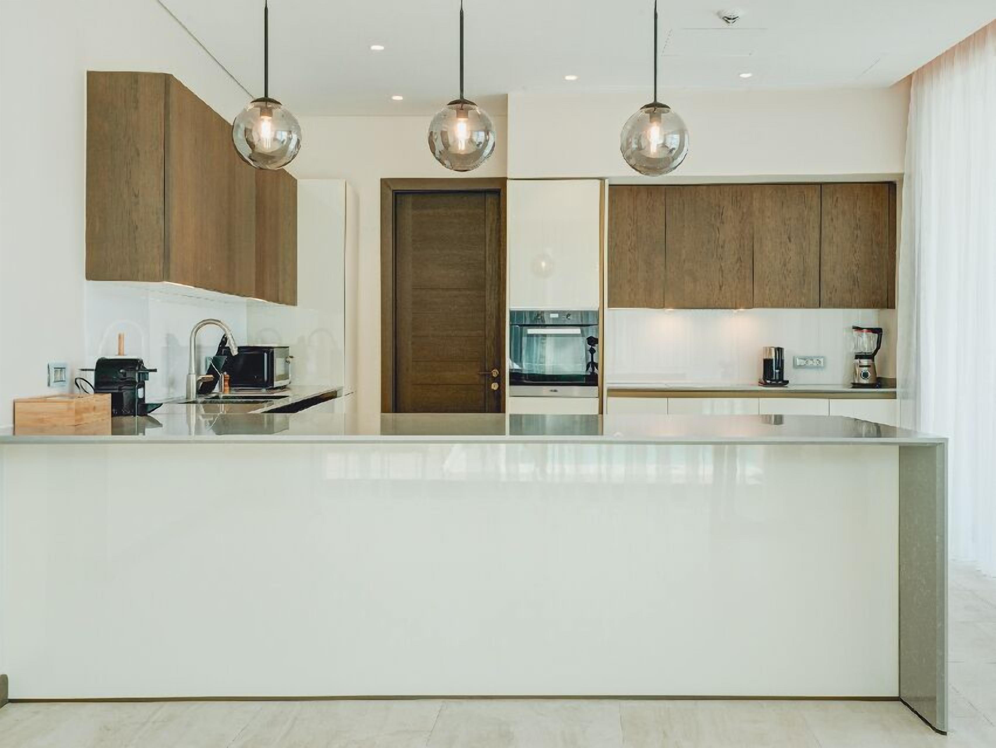 Una cocina moderna con una isla central, armarios de madera e iluminación colgante.