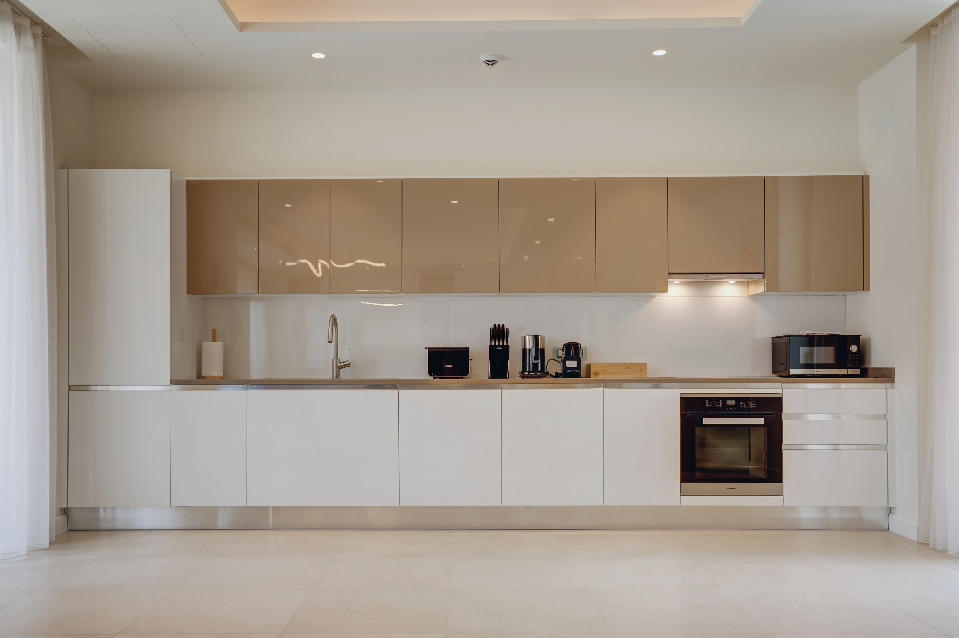 Una cocina moderna con gabinetes blancos, horno empotrado y microondas.