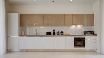 Una cocina moderna con gabinetes blancos, horno empotrado y microondas.