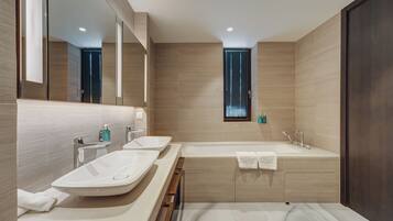 A modern bathroom with two sinks, a bathtub, and a large mirror.