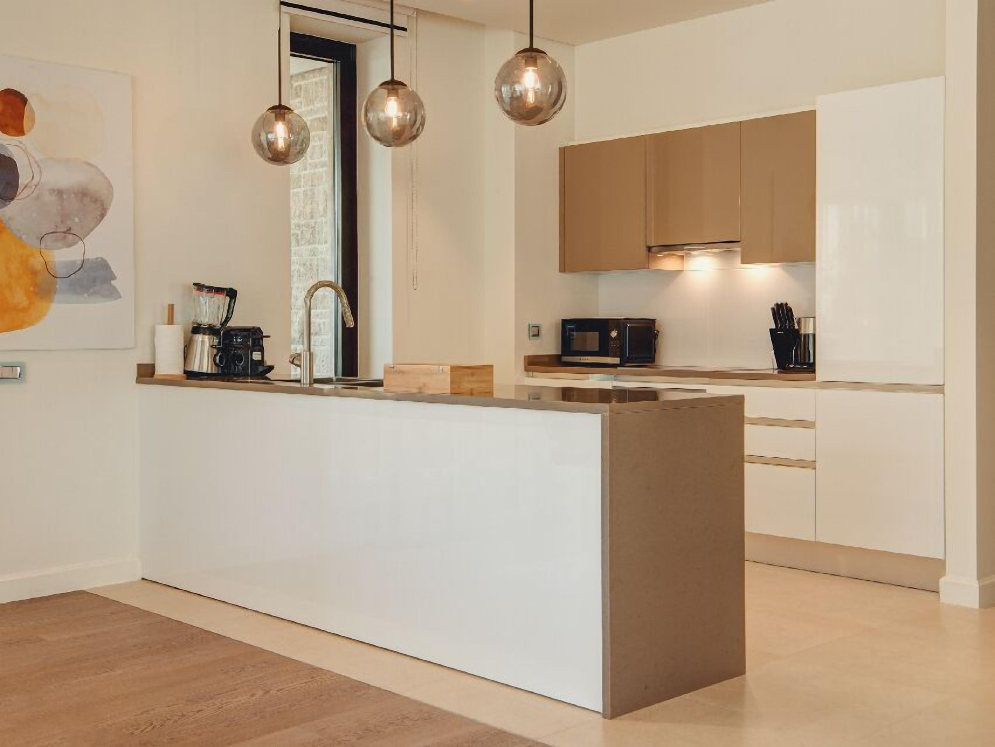 Una cocina moderna con una isla central, electrodomésticos de acero inoxidable e iluminación colgante.