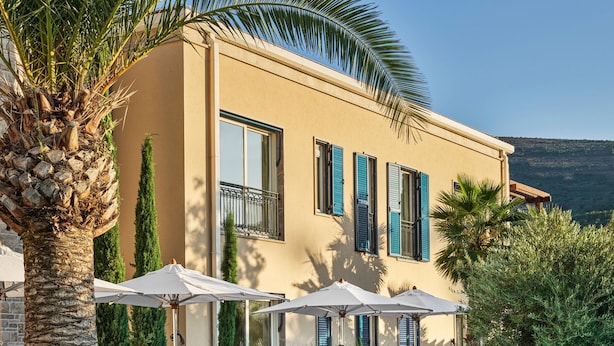 A poolside area with lounge chairs and umbrellas, a pool, and a building with balconies.