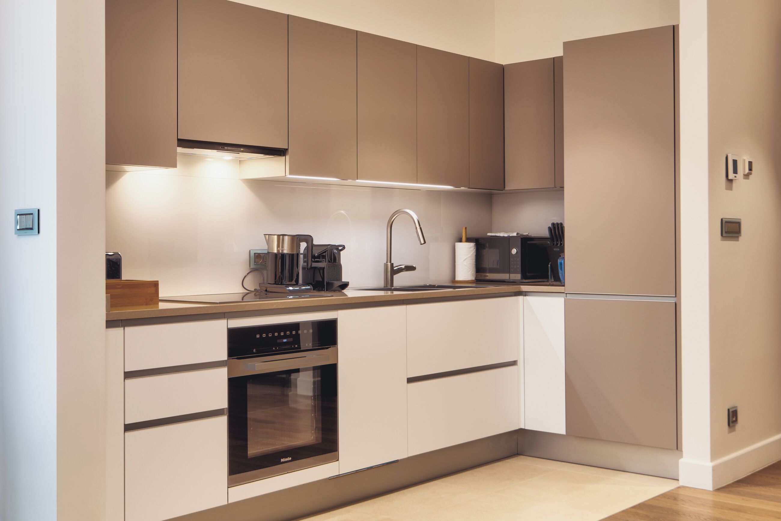 Una cocina moderna con electrodomésticos de acero inoxidable, horno empotrado y microondas.