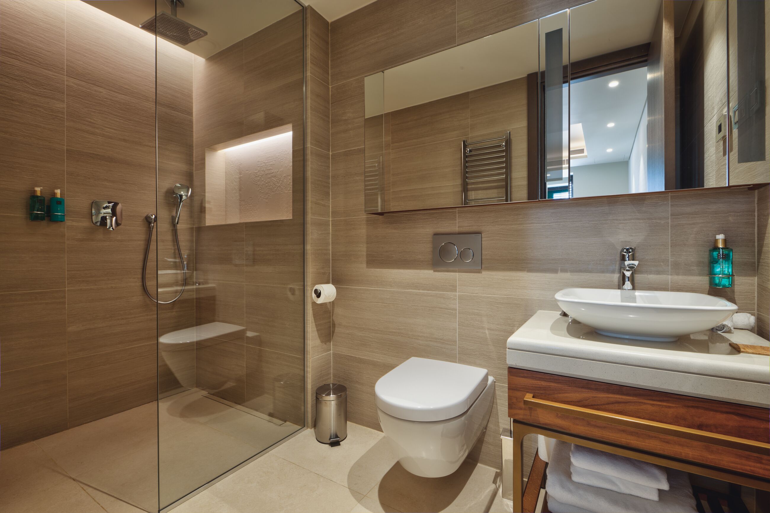 A modern bathroom with a glass shower enclosure, a toilet, a sink, and a mirror.
