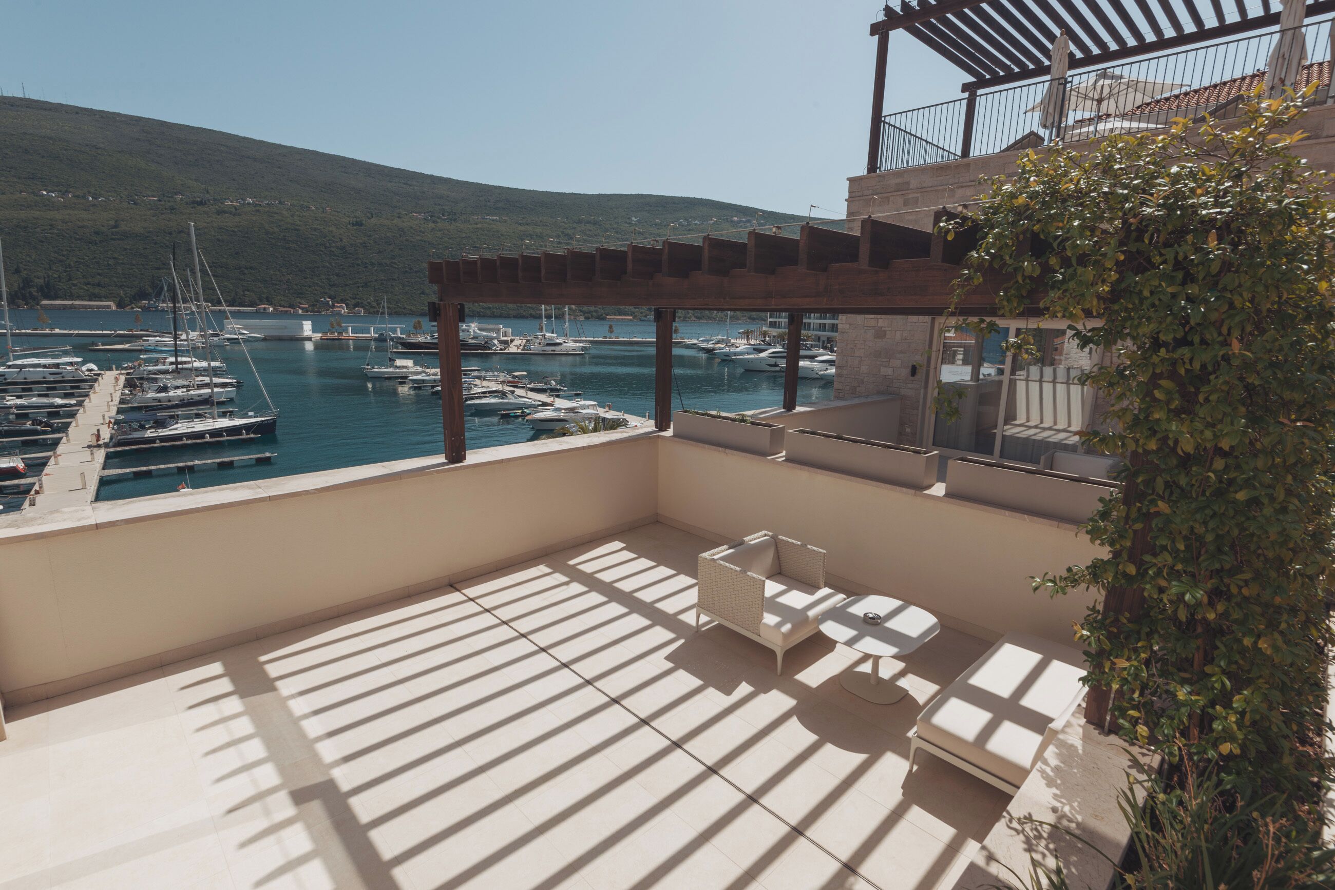 Varanda com vista para uma marina, mobiliário de exterior e um pérgola.