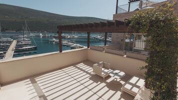 Varanda com vista para uma marina, mobiliário de exterior e um pérgola.