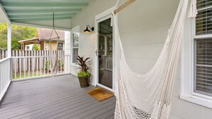 Eine Veranda mit einer Hängematte, einem Blumentopf und einer Tür zu einem überdachten Bereich.