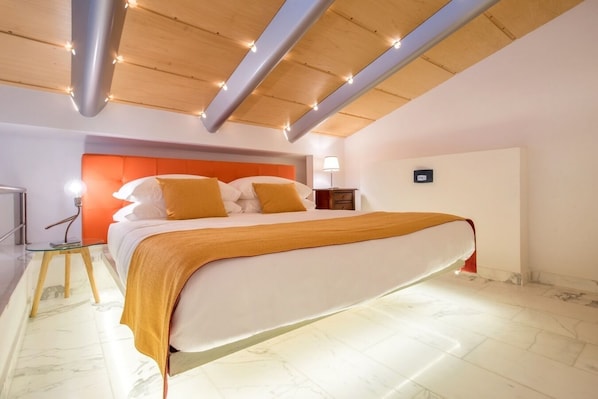 Un dormitorio moderno con una cama grande, vigas de madera en el techo y una mesita de noche con lámpara.