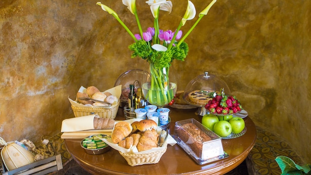 A breakfast buffet with bread, pastries, fruits, and flowers. - Da Rooms (Sorrento)