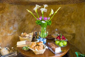 A breakfast buffet with bread, pastries, fruits, and flowers. - Da Rooms (Sorrento)