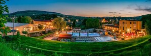 A hotel with a swimming pool, outdoor seating, and a view of the surrounding town and hills. - Septimia Hotels & Spa Resort (Odorheiu Secuiesc)