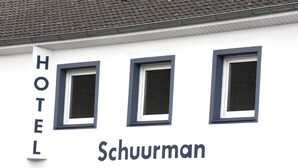 Un hotel llamado 'Schuurman' con tres ventanas y un cartel que indica el número 10.
