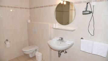 Een badkamer met toilet, wastafel, spiegel en handdoekhouder.