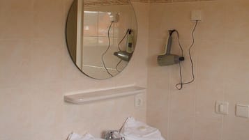 A bathroom with a round mirror, a white sink, and a towel rack.