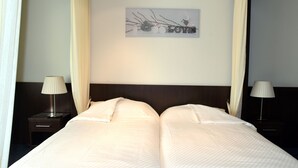 Una cama doble con cabecera oscura, dos lámparas de noche y una decoración en la pared con la palabra "LOVE".