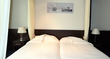 A double bed with a dark headboard, two bedside lamps, and a wall decoration with the word "LOVE".