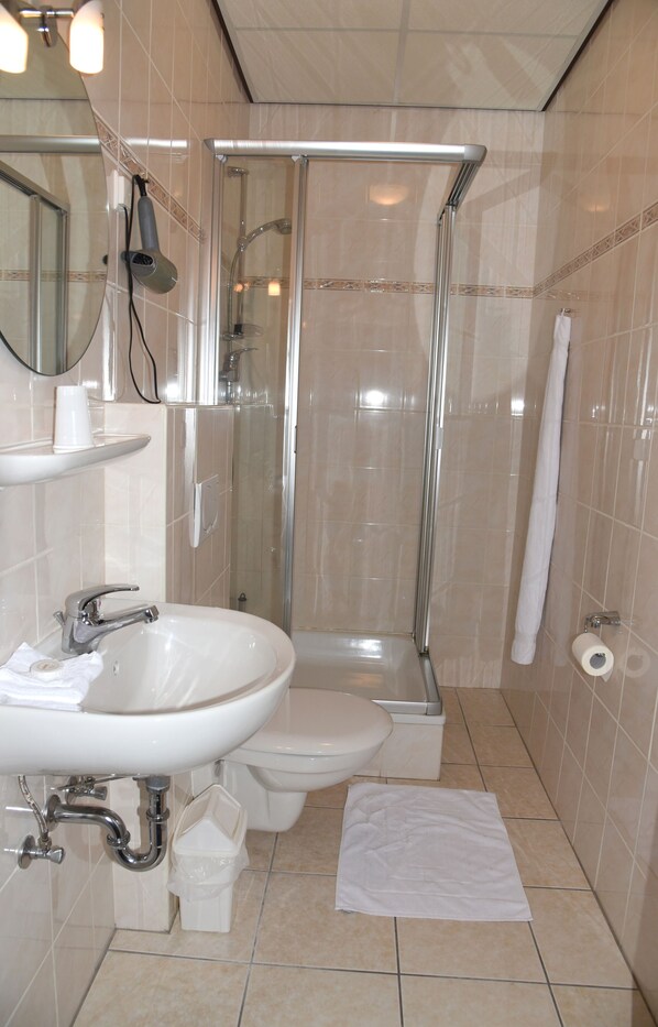 Un baño con lavamanos, inodoro y ducha con mampara de vidrio.