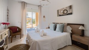 Hotellihuone, jossa on sänky, tuoli, työpöytä, lamppu ja ikkunasta avautuva näkymä ulos.