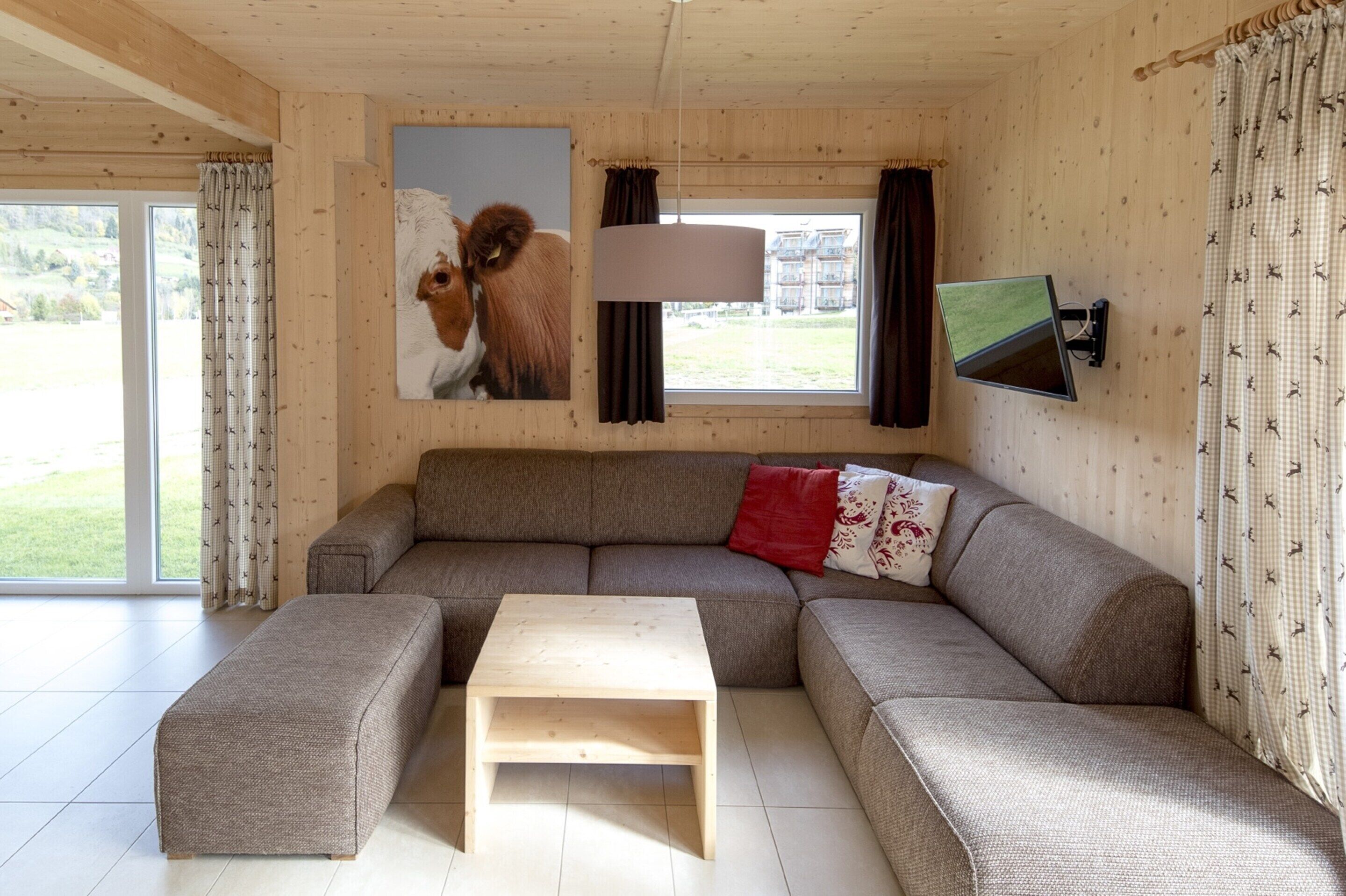 A cozy living room with a sectional sofa, a wooden coffee table, and a mounted TV.