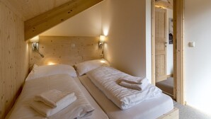 A wooden room with two beds, each with a headboard and bedside lamps.
