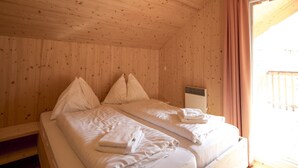 Een houten kamer met een bed, kussens en een raam met gordijnen.