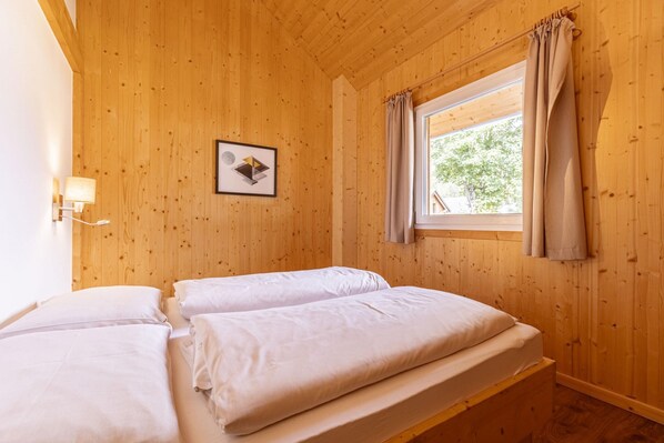 A wooden-paneled room with two beds, a window with curtains, and a wall-mounted lamp. - Voguish Apartment in Sankt Georgen ob Murau near Ski Area (Sankt Georgen am Kreischberg)