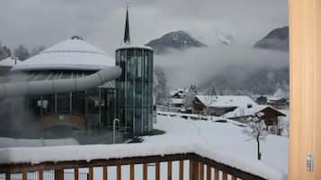 A snow-covered mountain landscape with a modern building featuring a cylindrical tower and a curved glass structure.