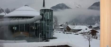 A snow-covered mountain landscape with a modern building featuring a cylindrical tower and a curved glass structure.